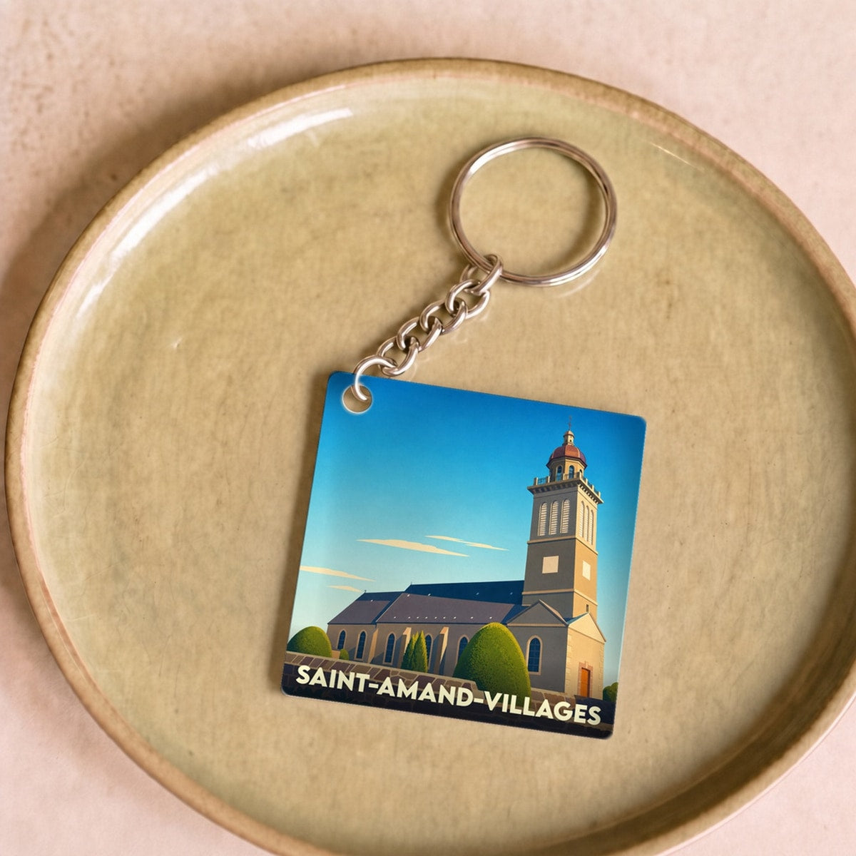 Porte-clés souvenir de la commune de Saint-Amand-Villages avec une illustration stylisée de son église.