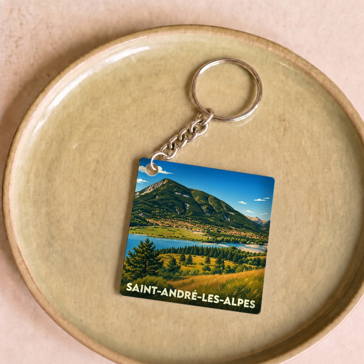 Porte-clés souvenir de la ville de Saint-André-les-Alpes avec une illustration stylisée de montagne et de lac.