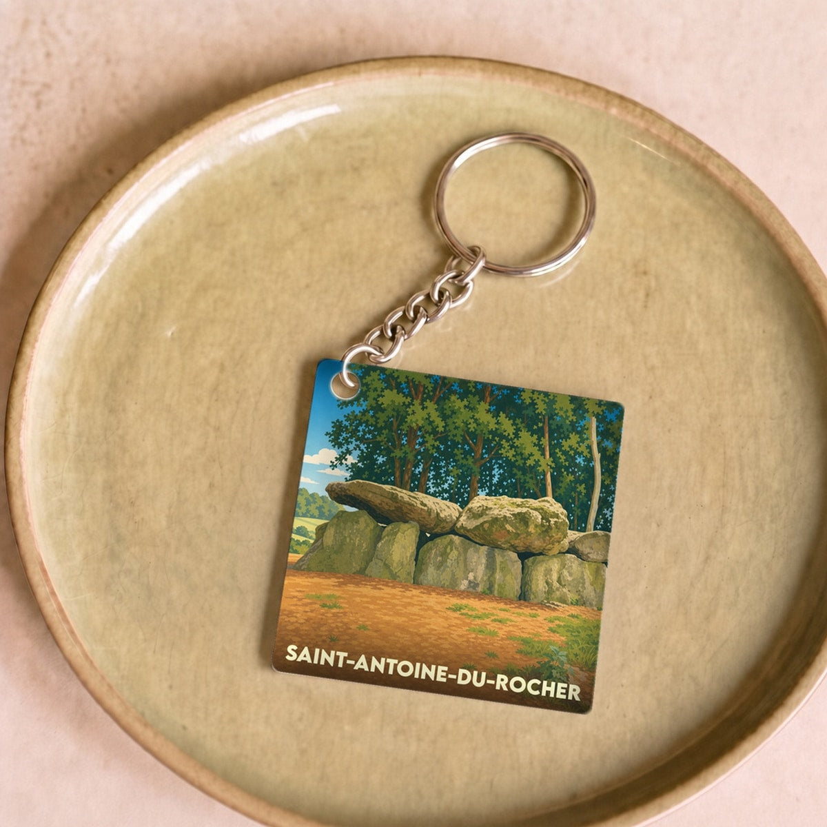Porte-clés souvenir de la ville de Saint-Antoine-du-Rocher avec une illustration stylisée d'un dolmen.