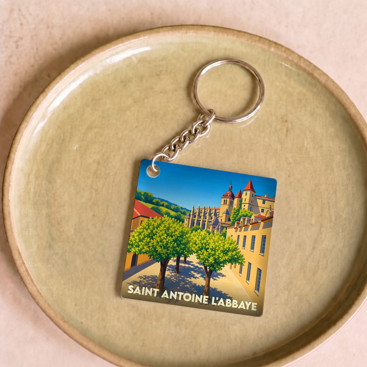 Porte-clés souvenir de Saint Antoine l'Abbaye avec une illustration stylisée du village et de son abbaye.