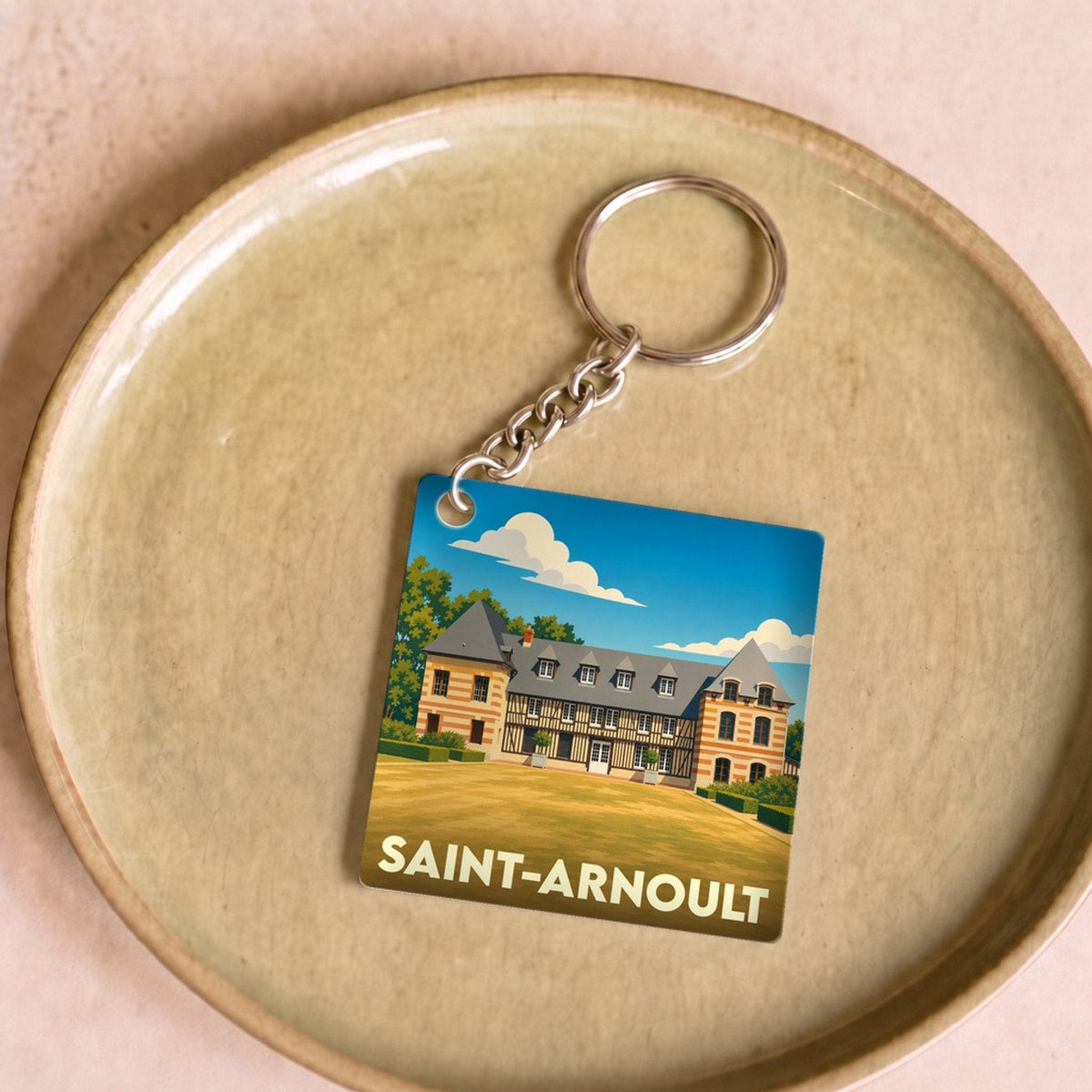 Porte-clés souvenir de la ville de Saint-Arnoult avec une illustration stylisée de son patrimoine.