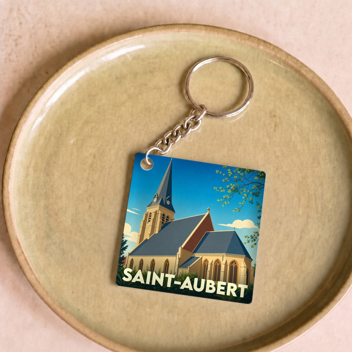 Porte-clés souvenir de la ville de Saint-Aubert avec une illustration stylisée de son église.