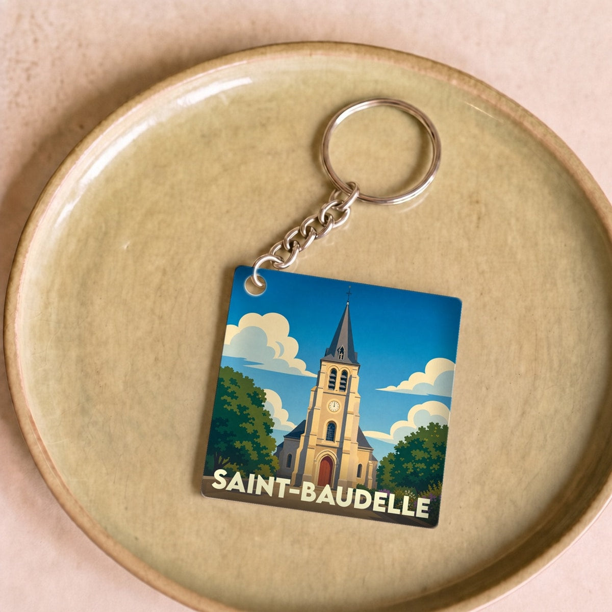 Porte-clés souvenir de la ville de Saint-Baudelle avec une illustration stylisée de son église.