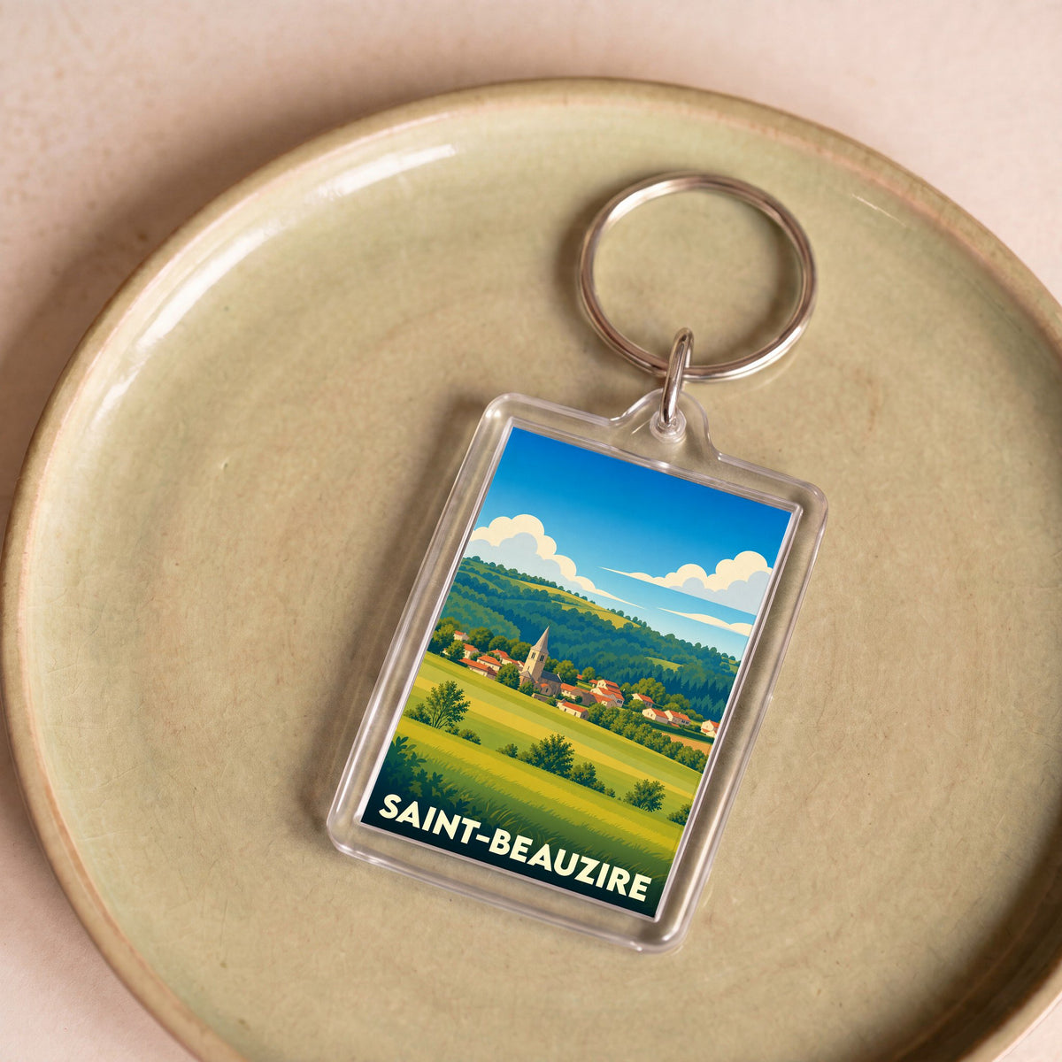 Porte-clés souvenir de la ville de Saint-Beauzire avec une illustration paysagère stylisée.