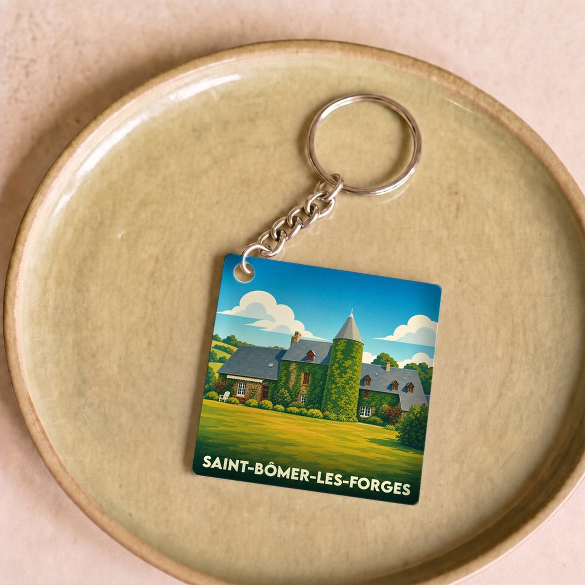 Porte-clés souvenir de la ville de Saint-Bômer-les-Forges avec une illustration stylisée d'un manoir normand.