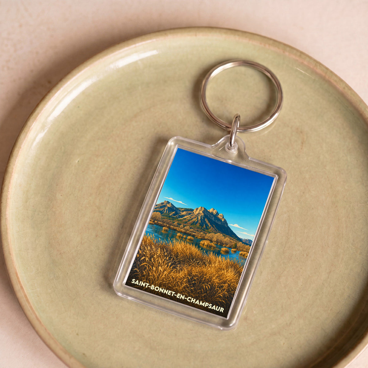 Porte-clés souvenir de la ville de Saint-Bonnet-en-Champsaur avec une illustration de paysage montagneux.