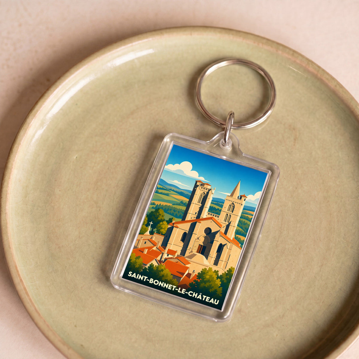 Porte-clés souvenir de la ville de Saint-Bonnet-le-Château avec une illustration stylisée de sa collégiale.