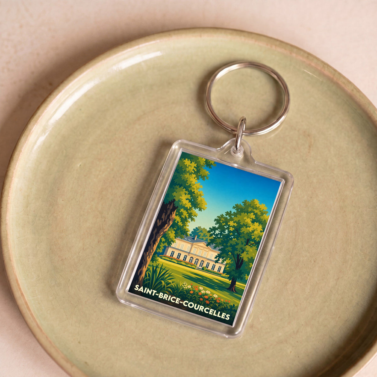 Porte-clés souvenir de la ville de Saint-Brice-Courcelles avec une illustration stylisée d'un château entouré de verdure.