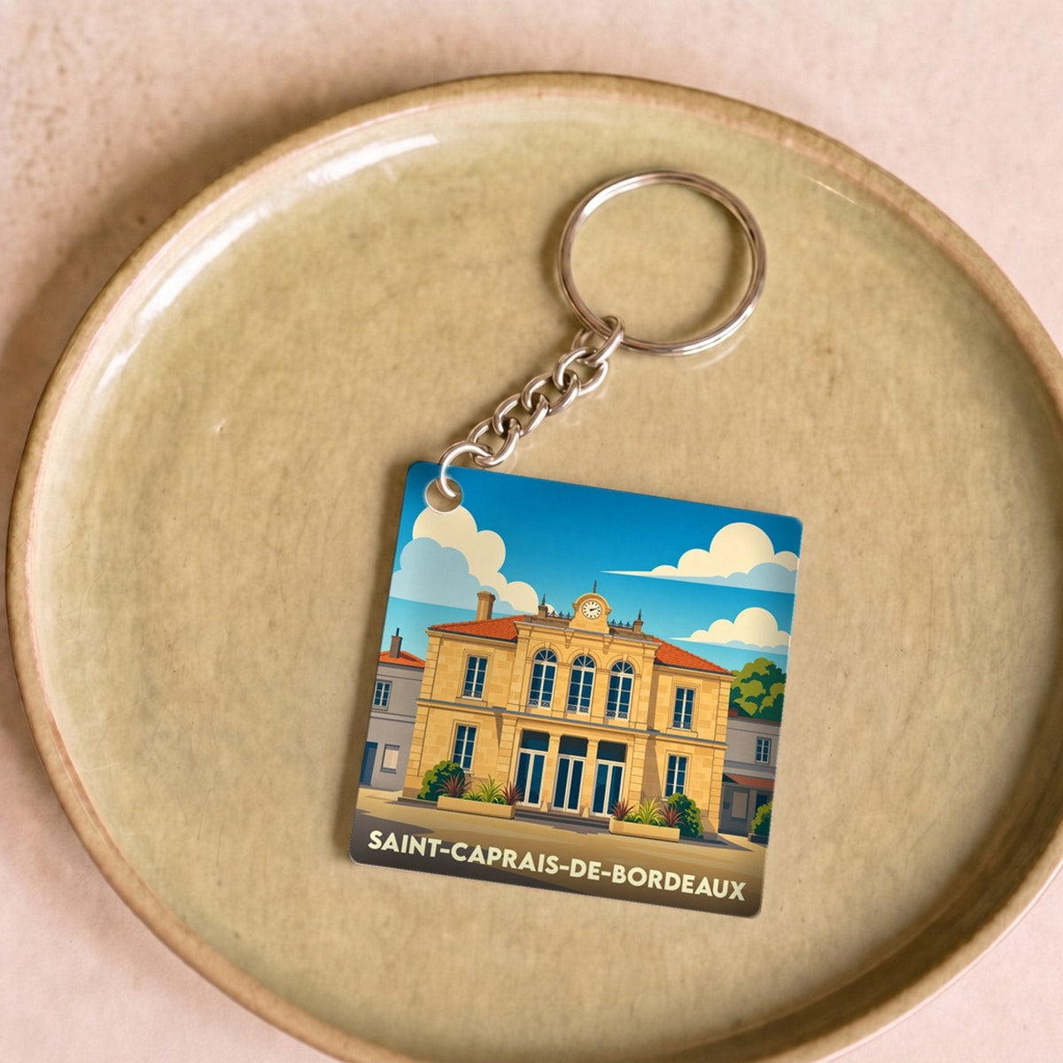 Porte-clés souvenir de la ville de Saint-Caprais-de-Bordeaux avec une illustration stylisée.