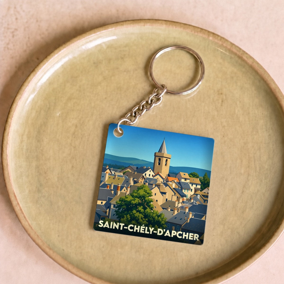 Porte-clés souvenir de la ville de Saint-Chély-d'Apcher avec une illustration stylisée.