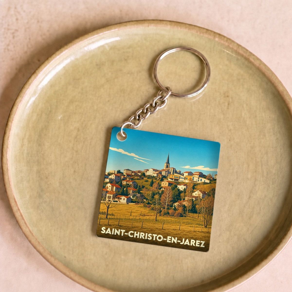 Porte-clés souvenir de la ville de Saint-Christo-en-Jarez avec une illustration stylisée du village.