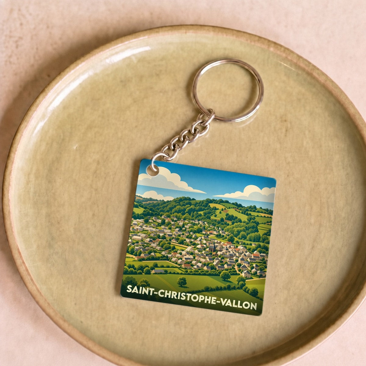 Porte-clés souvenir de la ville de Saint-Christophe-Vallon avec une illustration stylisée d'un paysage vallonné.