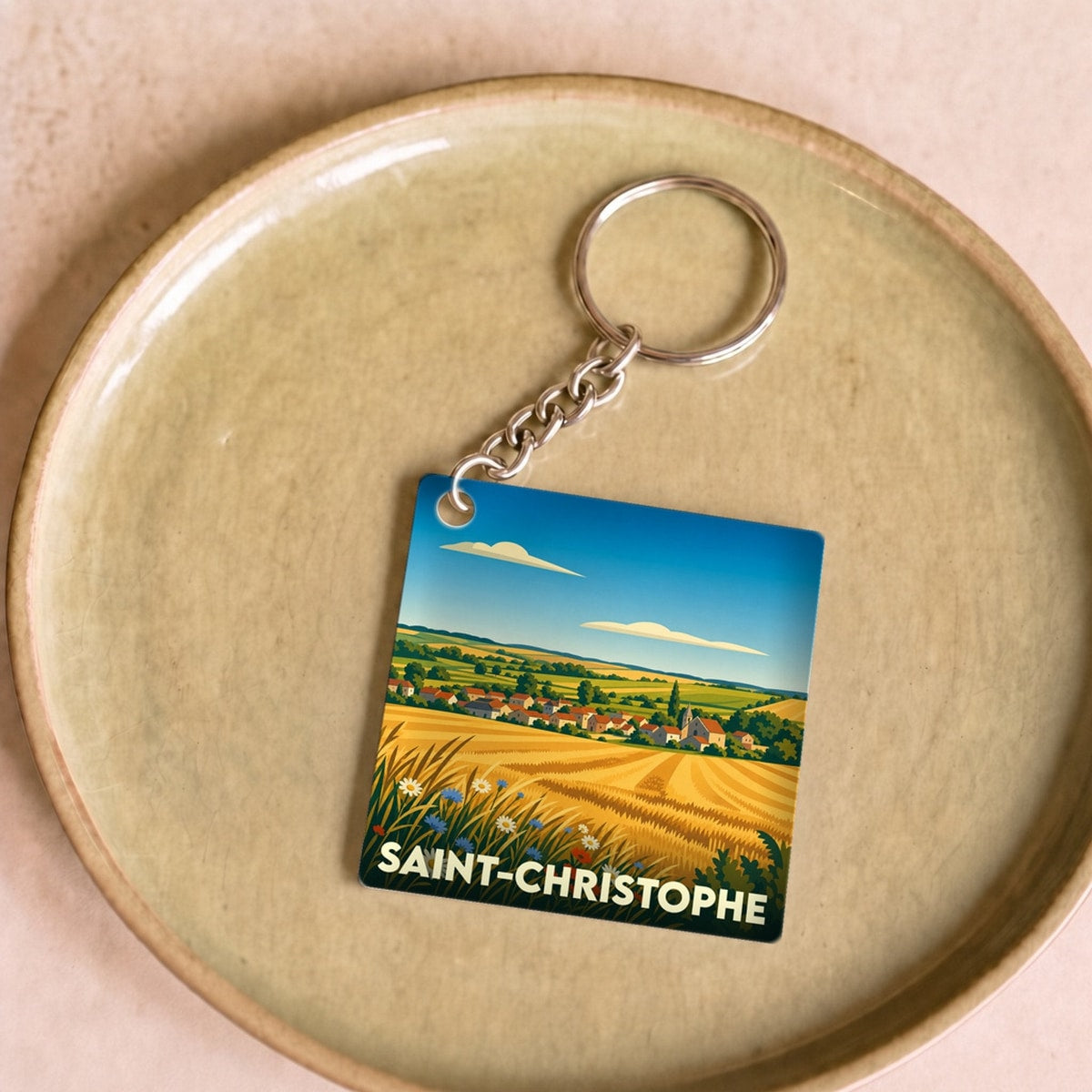 Porte-clés souvenir de la ville de Saint-Christophe avec une illustration stylisée de champs dorés et d'un village.