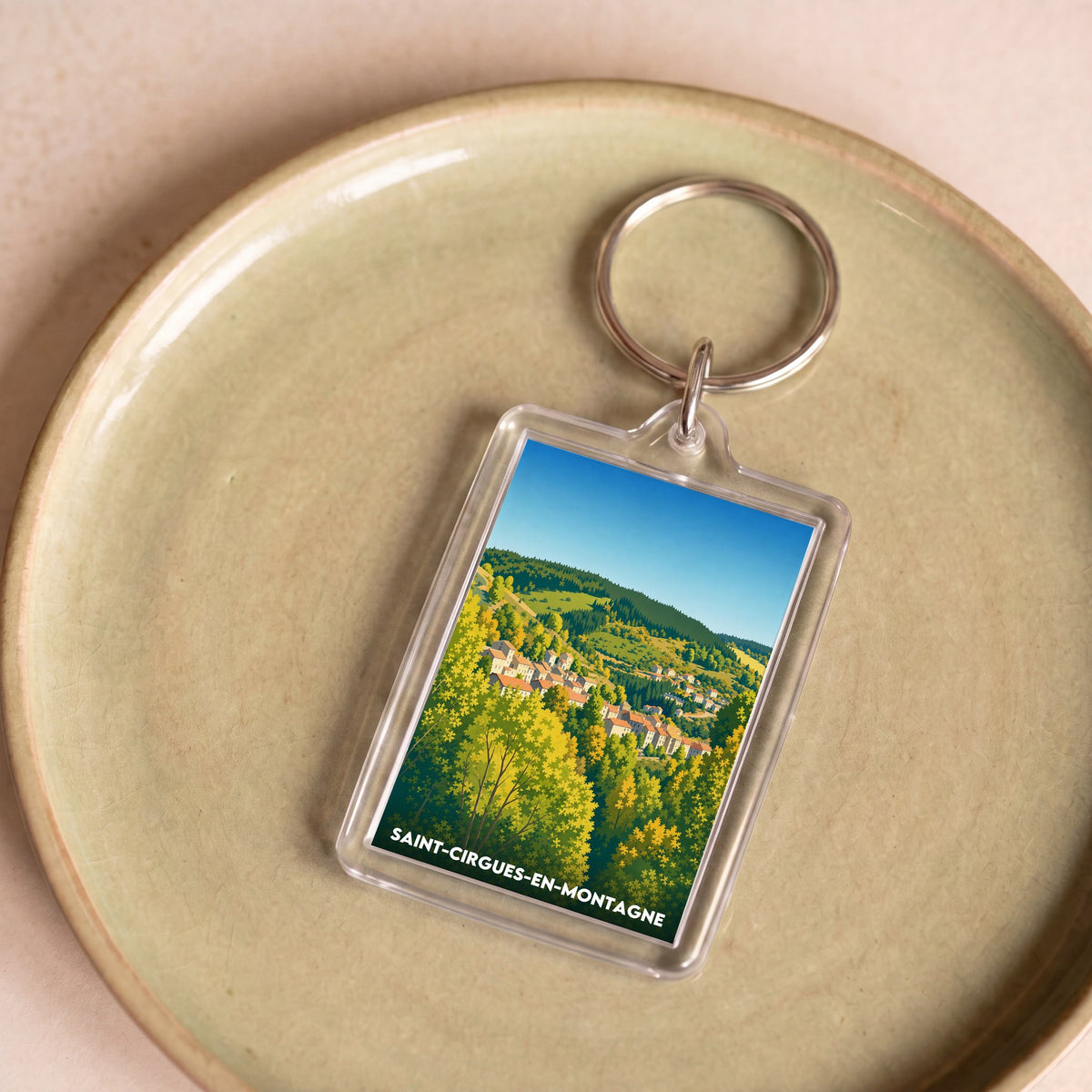 Porte-clés souvenir de la ville de Saint-Cirgues-en-Montagne avec une illustration stylisée.