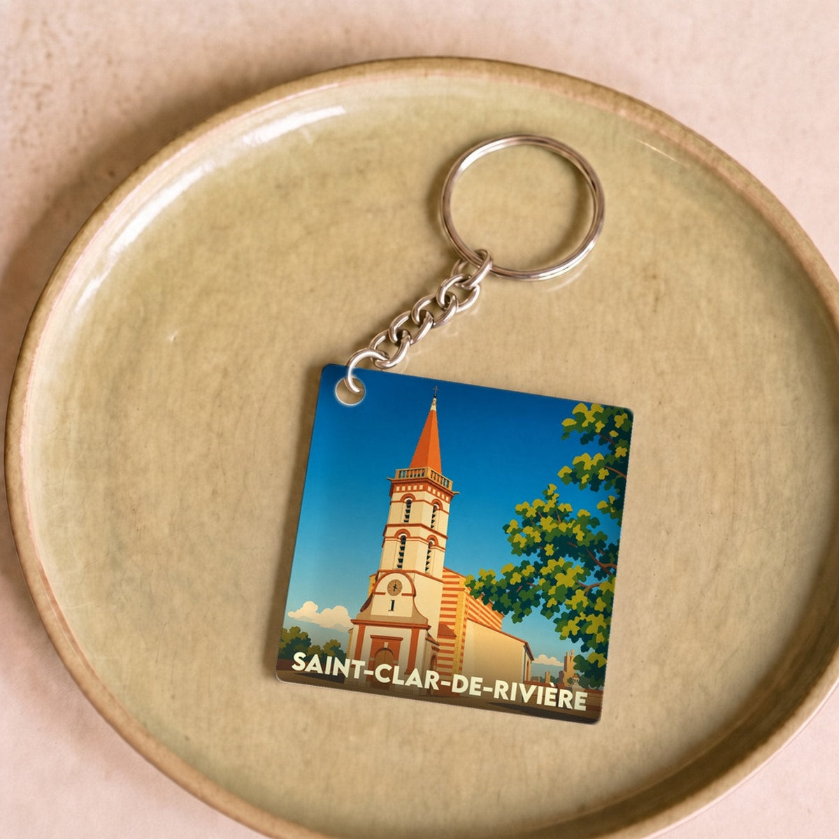 Porte-clés souvenir de la ville de Saint-Clar-de-Rivière avec une illustration stylisée de son église.