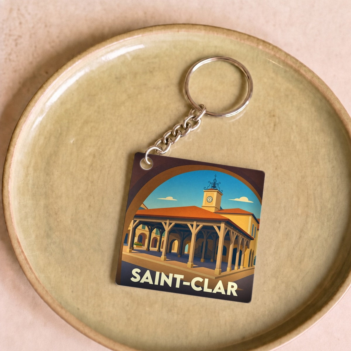 Porte-clés souvenir de la ville de Saint-Clar avec une illustration stylisée de sa halle médiévale.