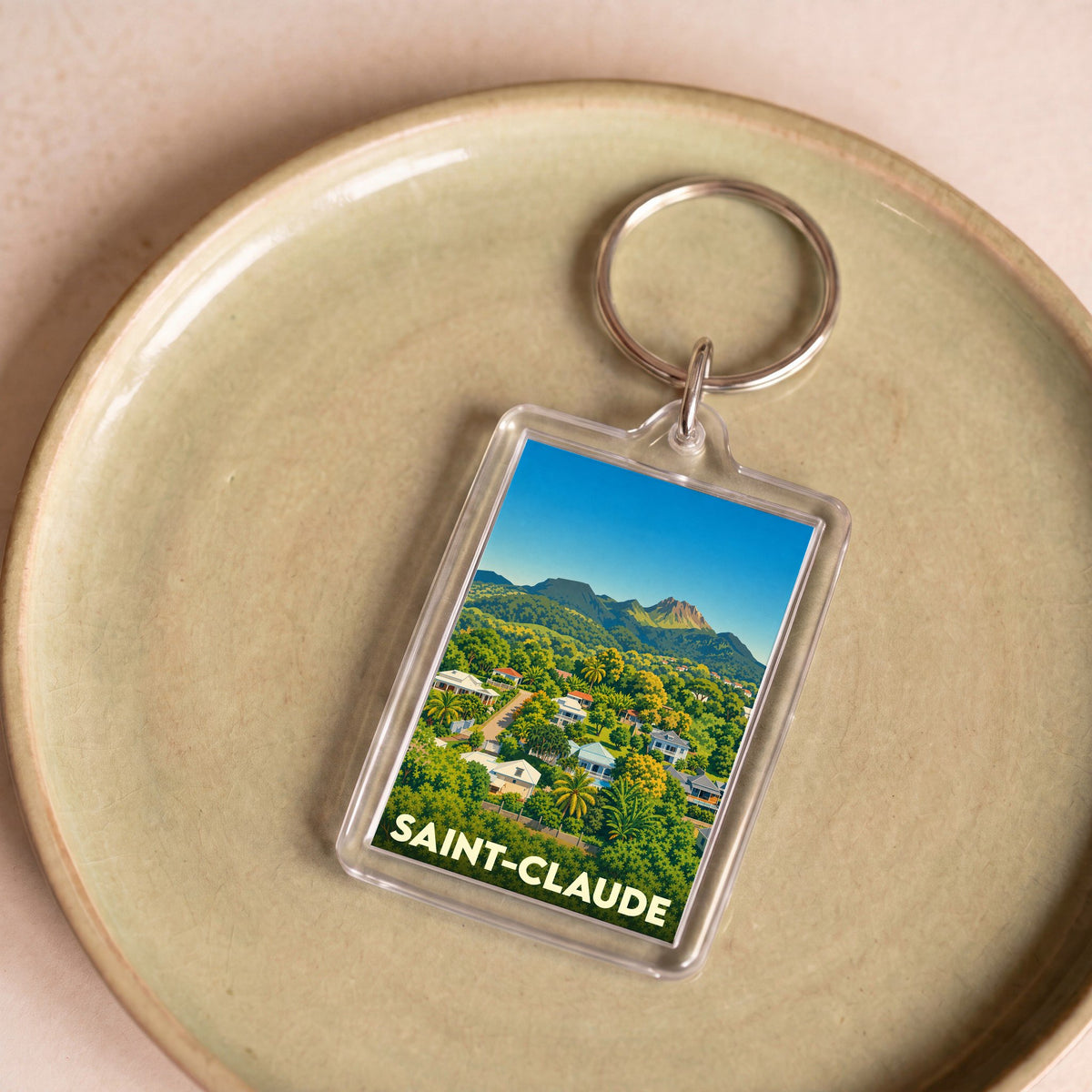 Porte-clés rectangulaire souvenir de la ville de Saint-Claude illustrant un paysage tropical montagneux.
