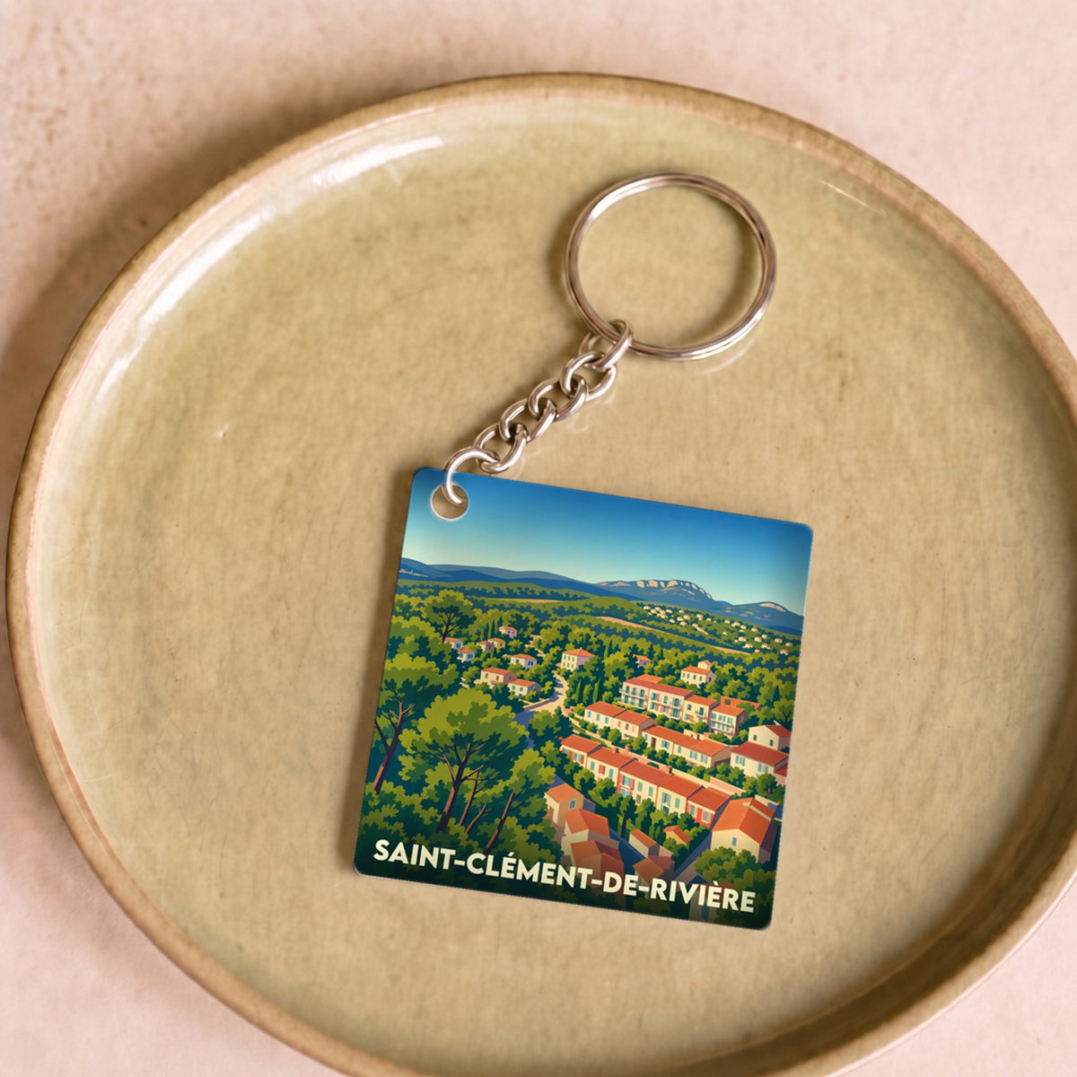 Porte-clés souvenir de la ville de Saint-Clément-de-Rivière avec une illustration stylisée.