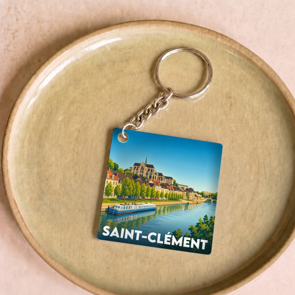 Porte-clés souvenir de la ville de Saint-Clément avec une illustration stylisée d'un paysage fluvial.