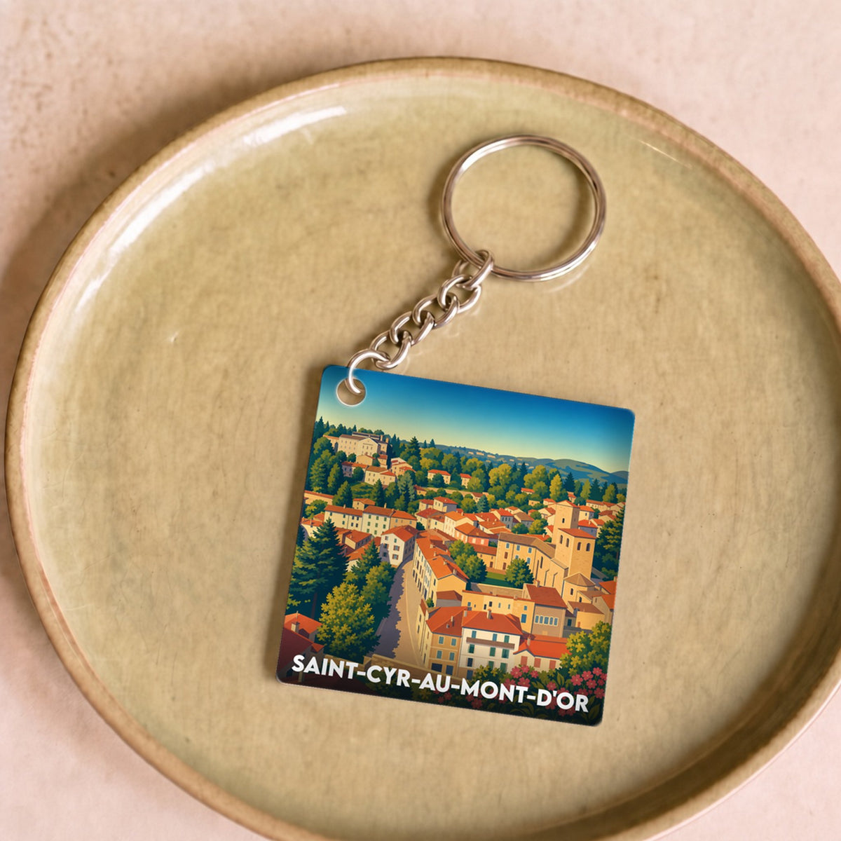 Porte-clés souvenir de la ville de Saint-Cyr-au-Mont-d'Or avec une illustration stylisée et colorée du village.