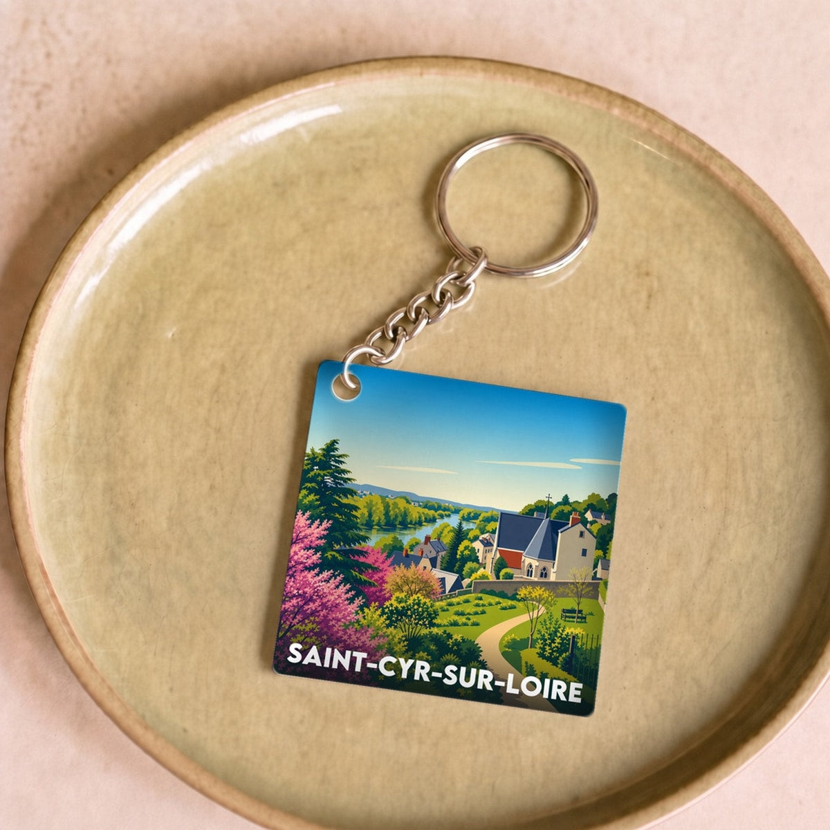 Porte-clés souvenir de la ville de Saint-Cyr-sur-Loire avec une illustration stylisée.