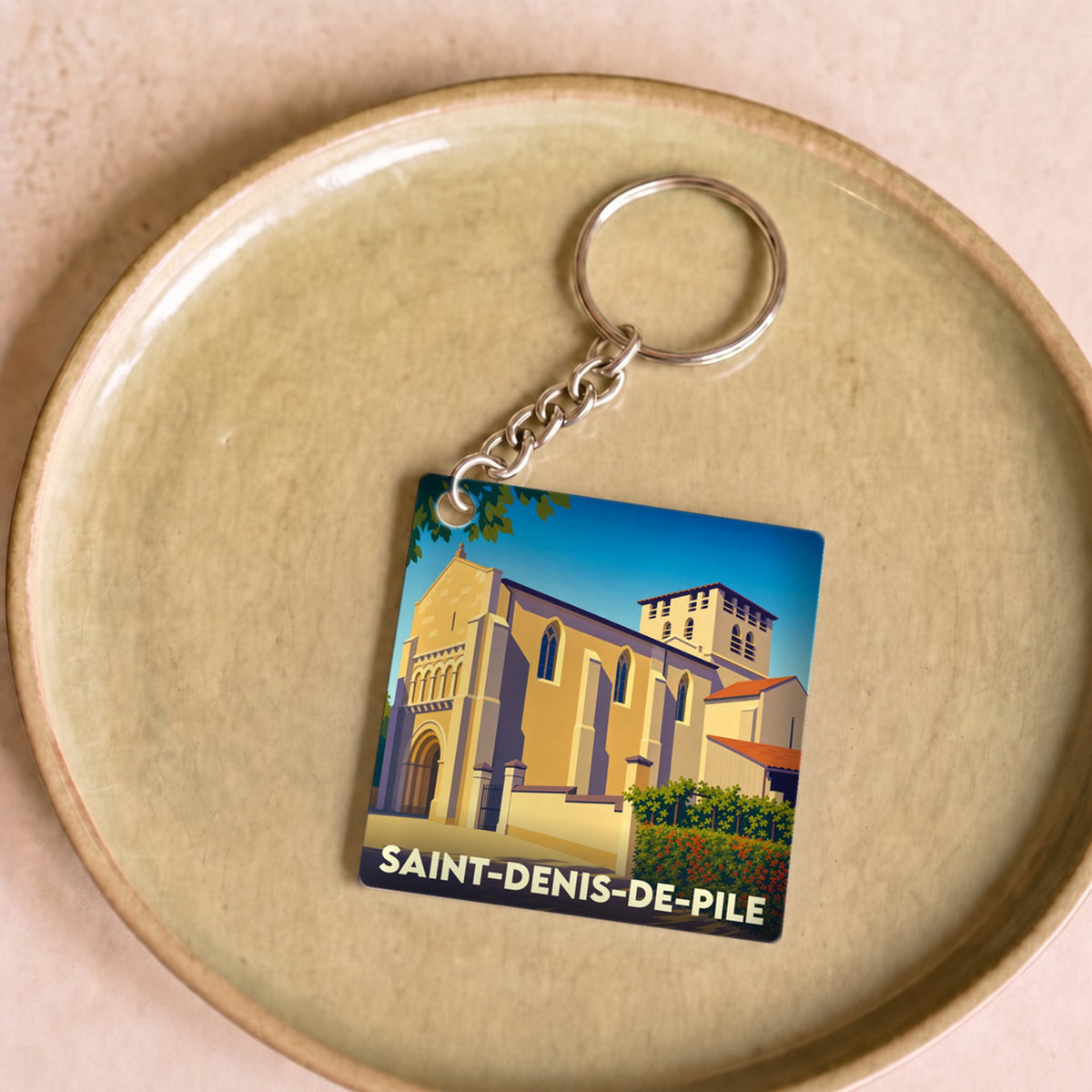 Porte-clés souvenir de la ville de Saint-Denis-de-Pile avec une illustration stylisée de son église.