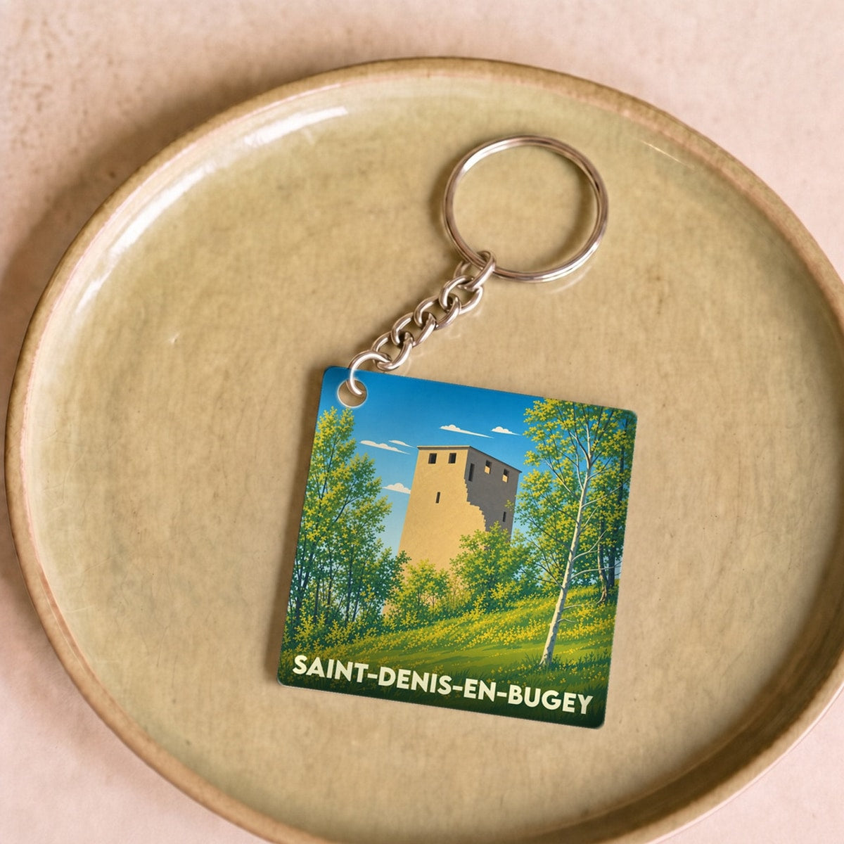 Porte-clés souvenir de la ville de Saint-Denis-en-Bugey illustrant une tour médiévale entourée de verdure.