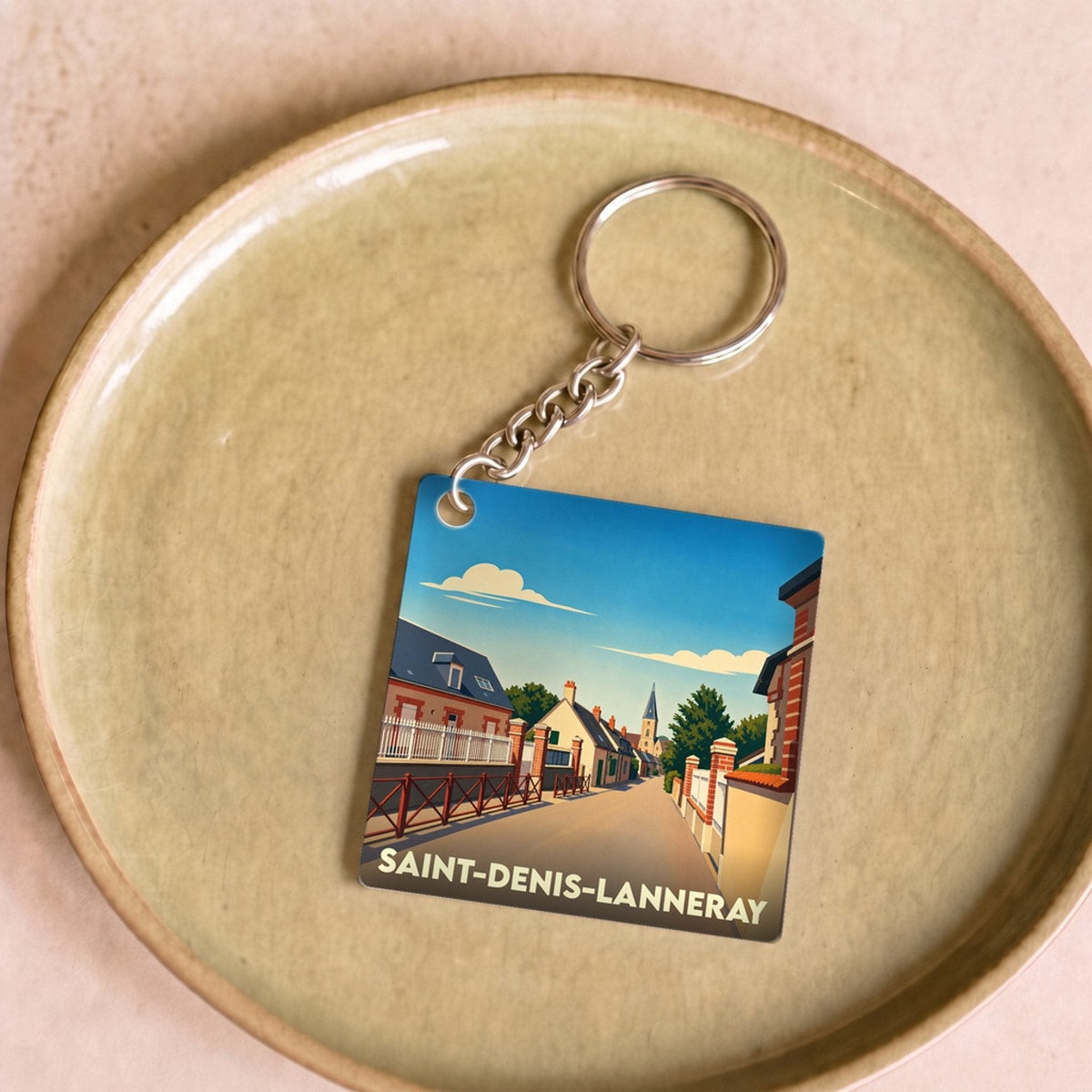 Porte-clés souvenir de la commune de Saint-Denis-Lanneray avec une illustration stylisée de son paysage urbain.