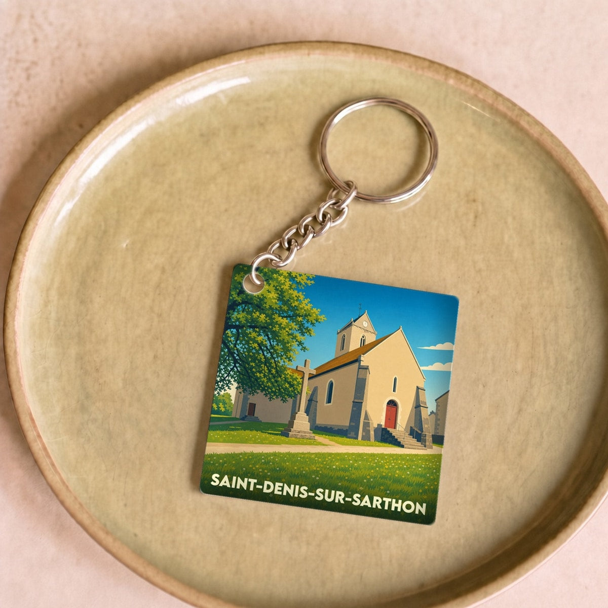 Porte-clés souvenir de la ville de Saint-Denis-sur-Sarthon avec une illustration stylisée de son église.
