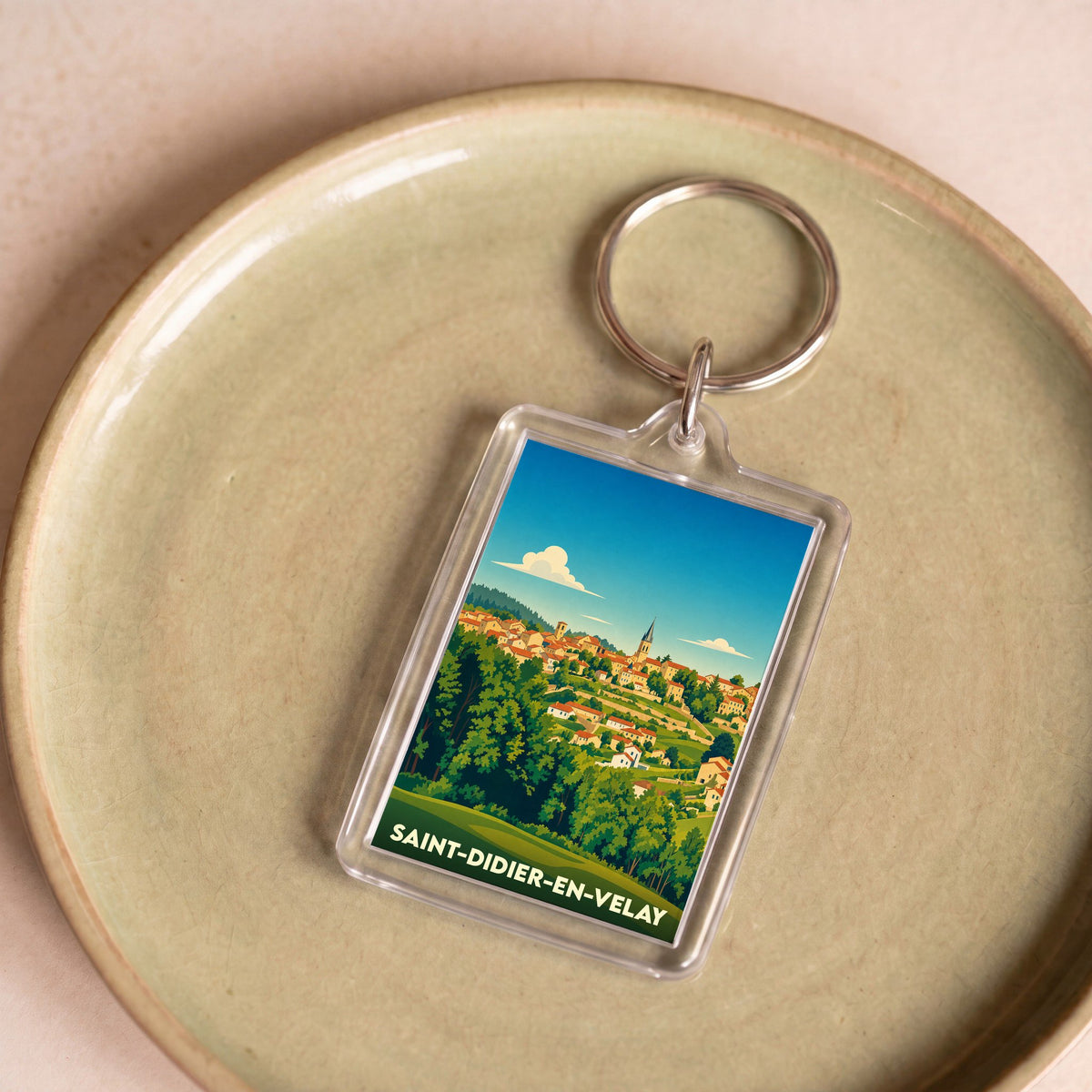 Porte-clés souvenir de la ville de Saint-Didier-en-Velay avec une illustration paysagère stylisée.