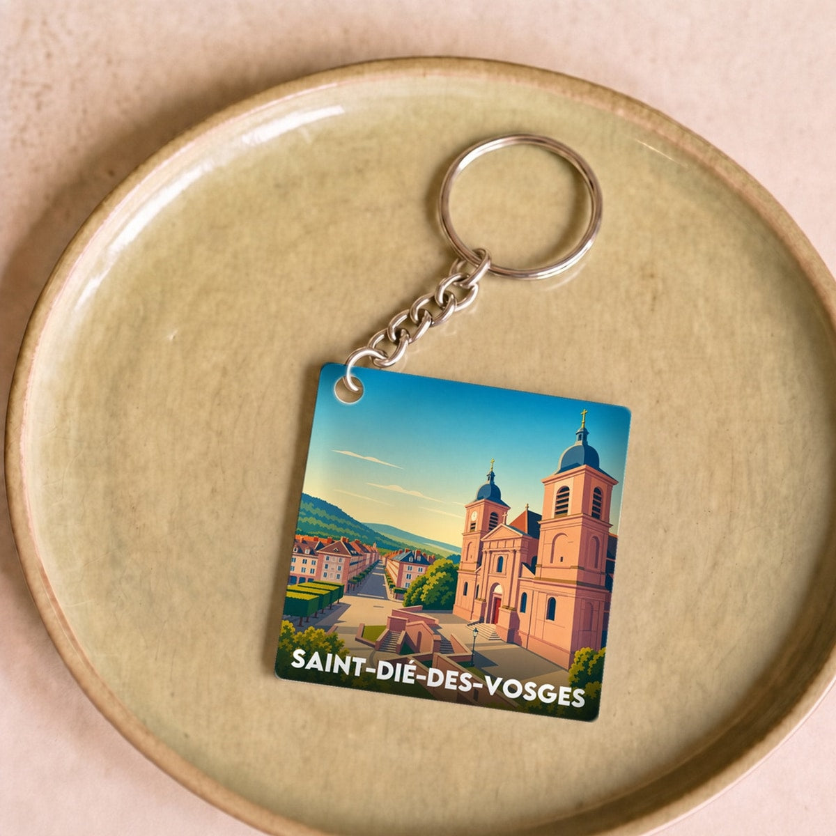 Porte-clés souvenir de la ville de Saint-Dié-des-Vosges avec une illustration stylisée.