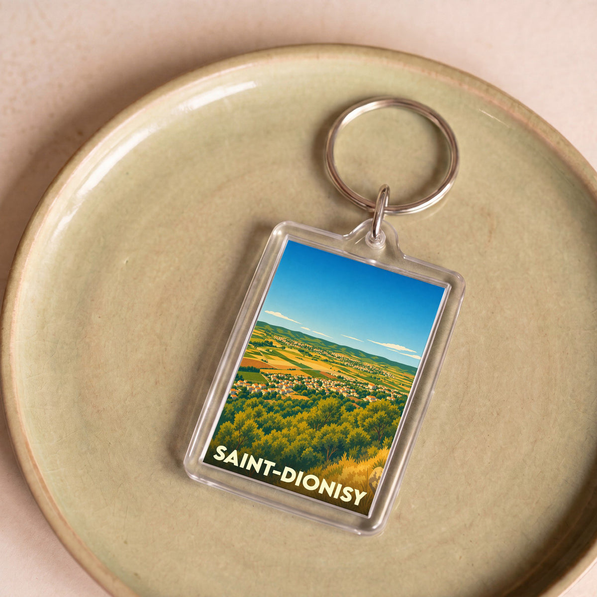 Porte-clés souvenir de la ville de Saint-Dionisy avec une illustration stylisée d'un paysage panoramique.