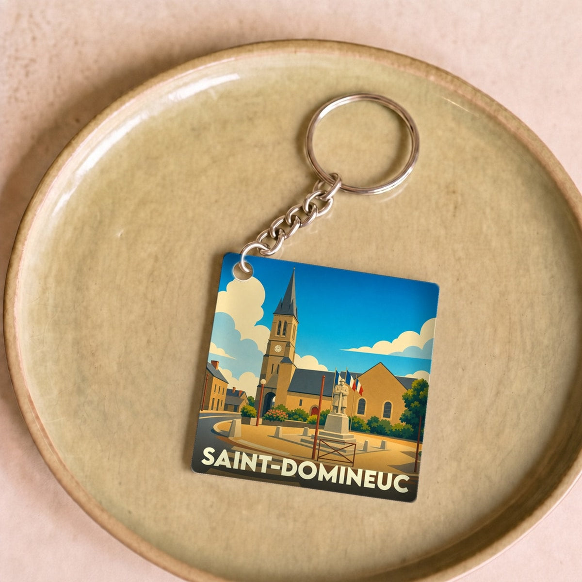 Porte-clés souvenir de la ville de Saint-Domineuc avec une illustration stylisée.