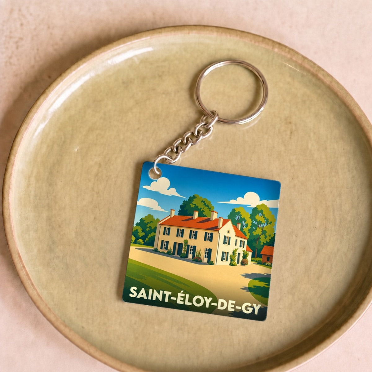 Porte-clés souvenir de la ville de Saint-Éloy-de-Gy avec une illustration stylisée d'une maison de campagne.