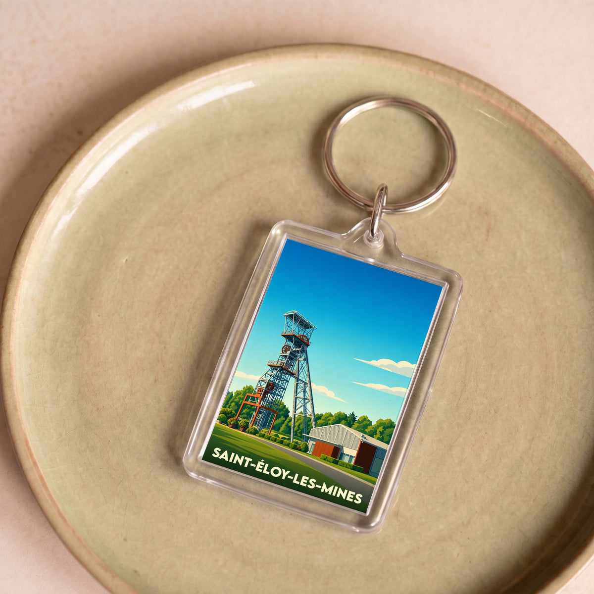 Porte-clés souvenir de la ville de Saint-Éloy-les-Mines avec une illustration stylisée d'un chevalement de mine.