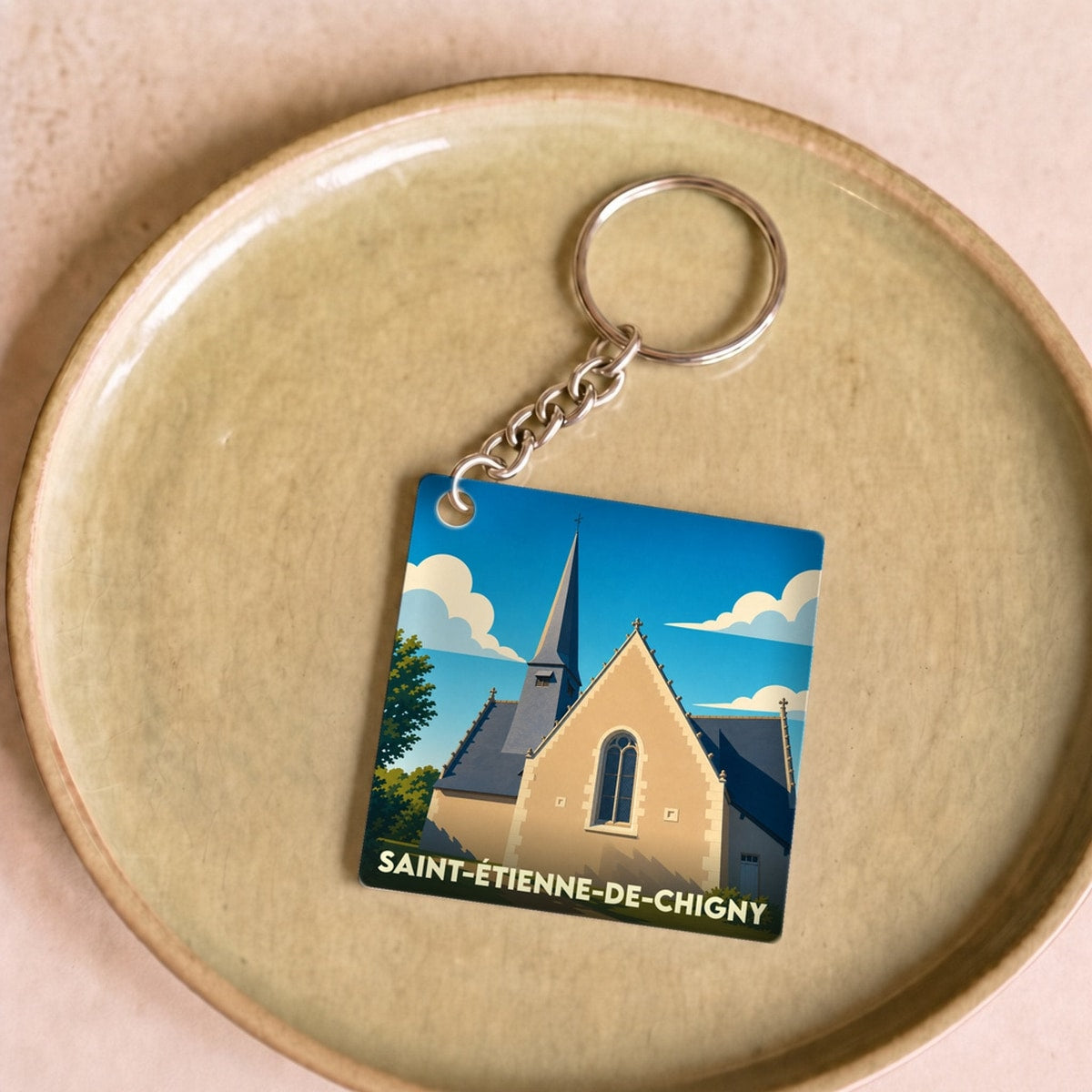 Porte-clés souvenir de la ville de Saint-Étienne-de-Chigny avec une illustration stylisée de son église.
