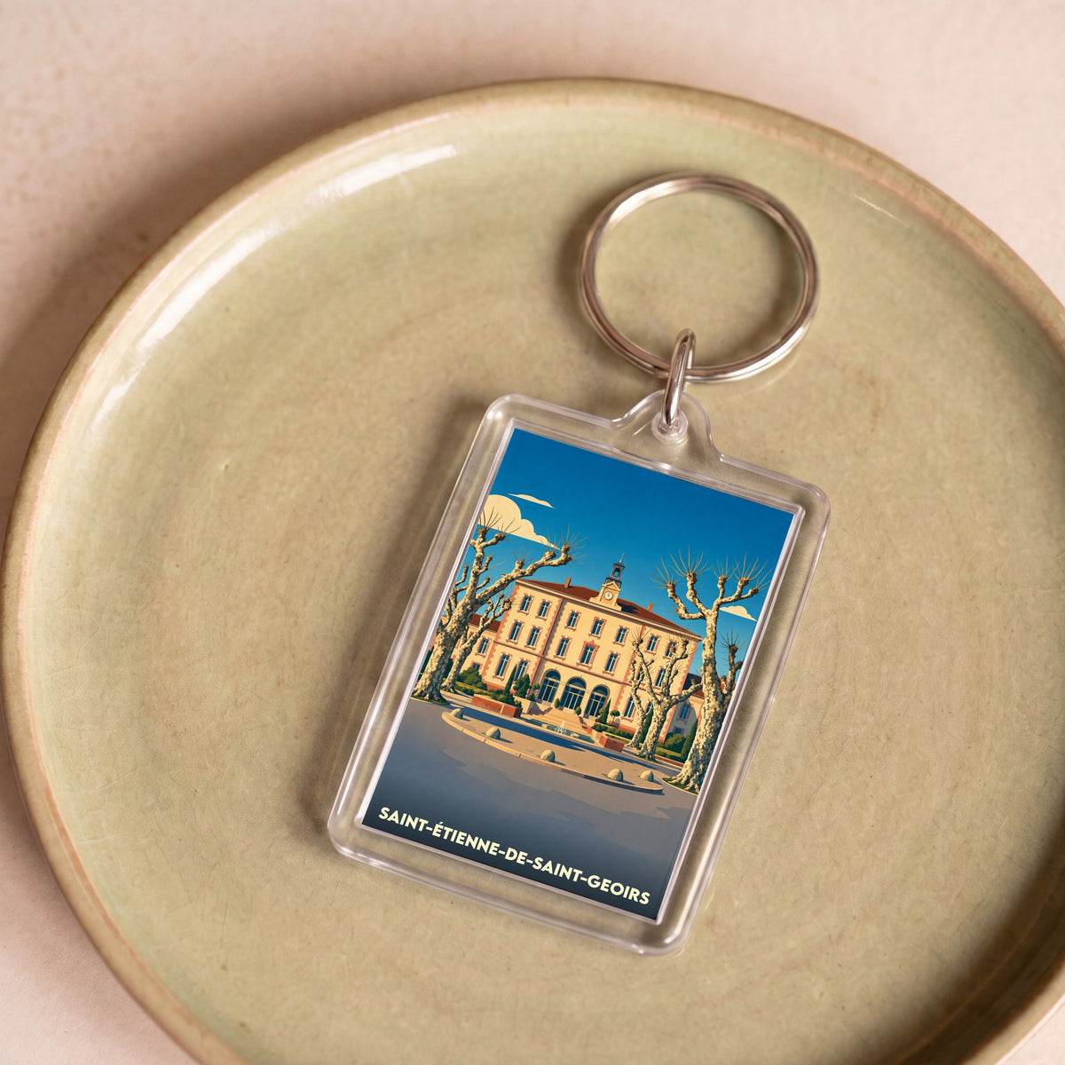 Porte-clés souvenir de la ville de Saint-Étienne-de-Saint-Geoirs avec une illustration stylisée.