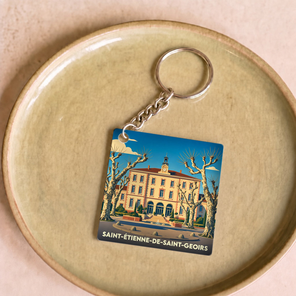 Porte-clés souvenir de la ville de Saint-Étienne-de-Saint-Geoirs avec une illustration stylisée.