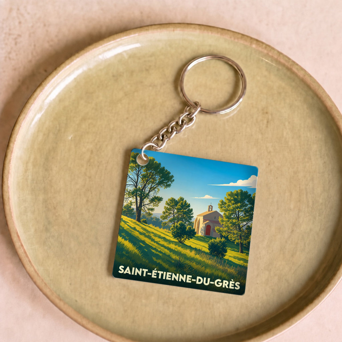 Porte-clés souvenir de la ville de Saint-Étienne-du-Grès avec une illustration stylisée.