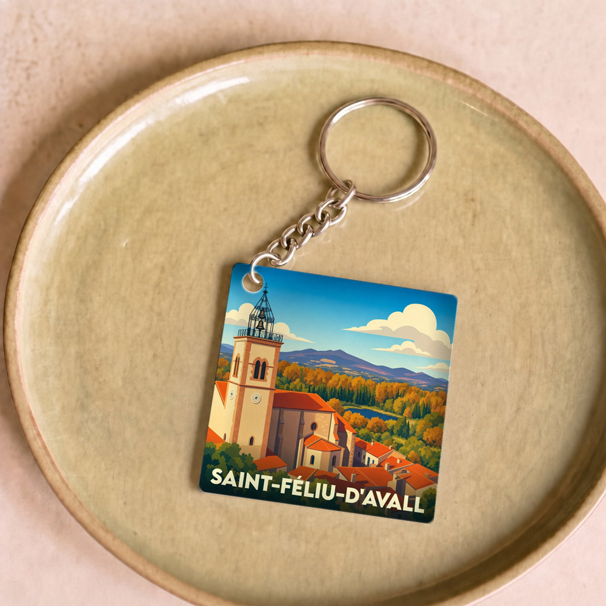 Porte-clés souvenir de la ville de Saint-Féliu-d'Avall avec une illustration stylisée.
