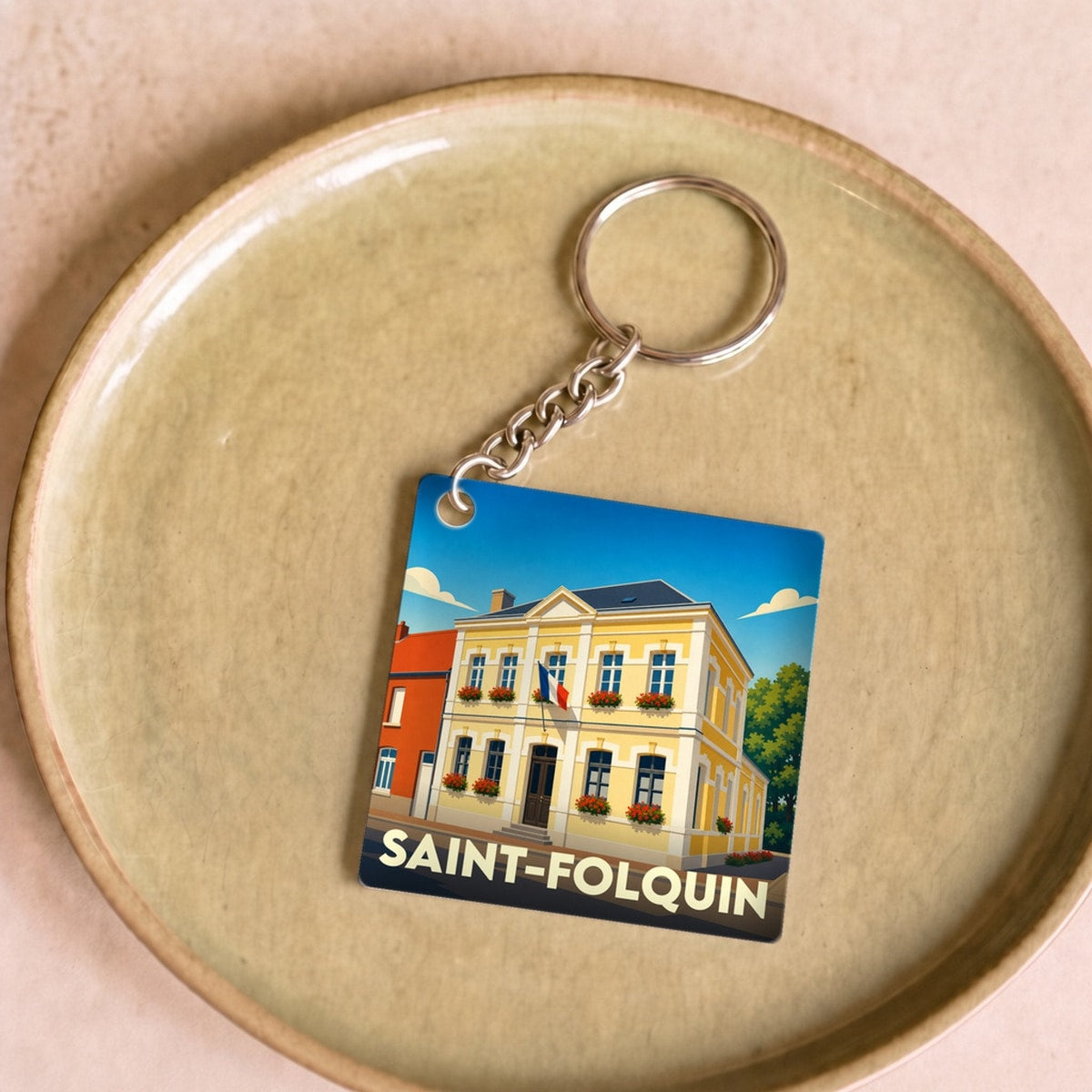 Porte-clés souvenir de la ville de Saint-Folquin avec une illustration stylisée de sa mairie.