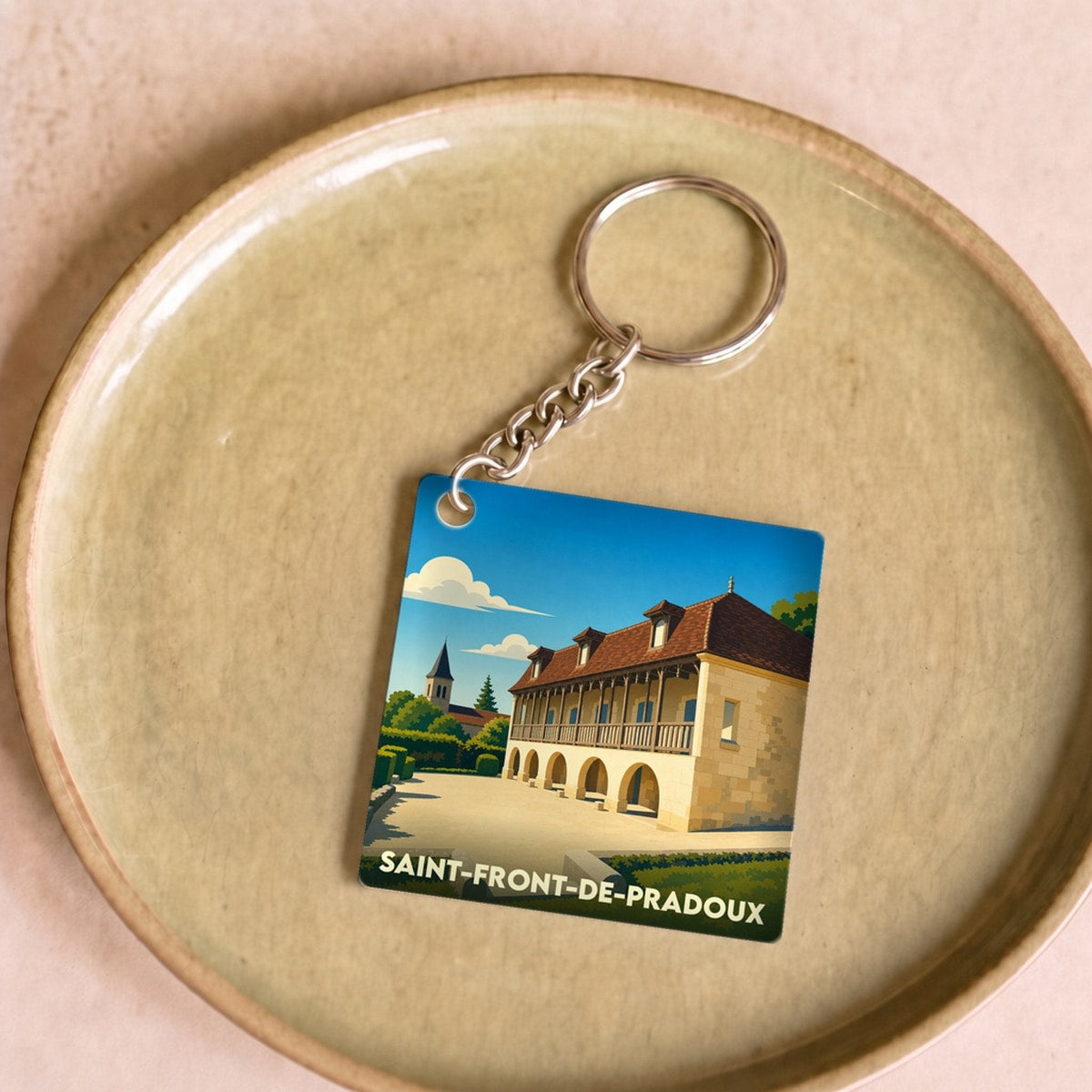 Porte-clés souvenir de Saint-Front-de-Pradoux avec une illustration stylisée de son patrimoine architectural.