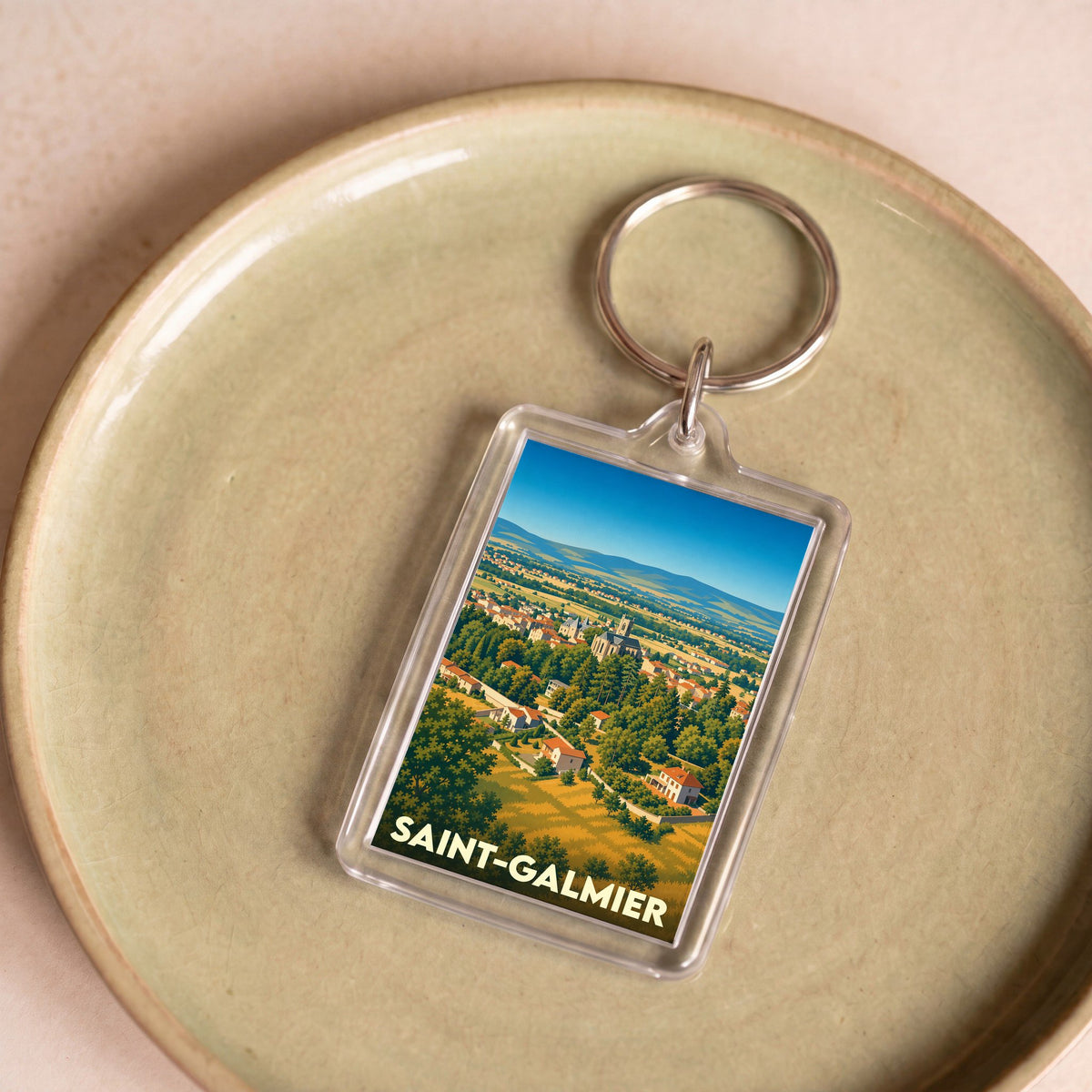 Porte-clés souvenir de la ville de Saint-Galmier avec une illustration stylisée de son paysage urbain et naturel.