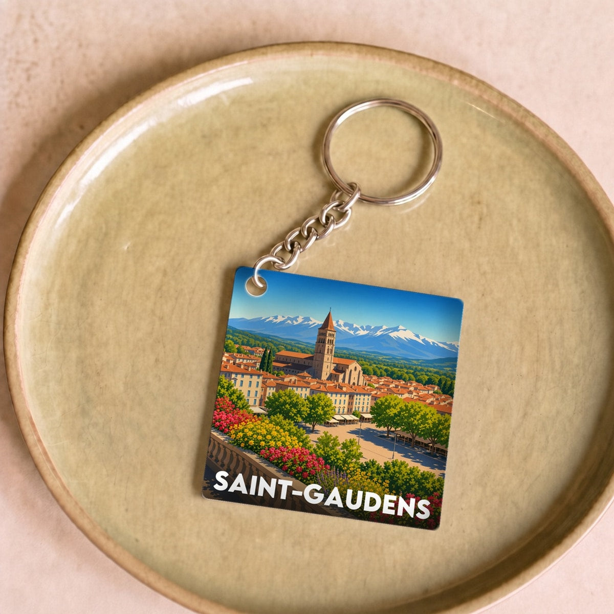 Porte-clés souvenir de la ville de Saint-Gaudens avec une illustration stylisée.