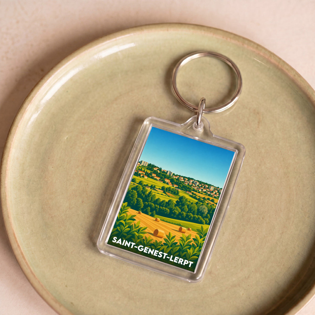 Porte-clés souvenir de la ville de Saint-Genest-Lerpt avec une illustration stylisée de son paysage vallonné.