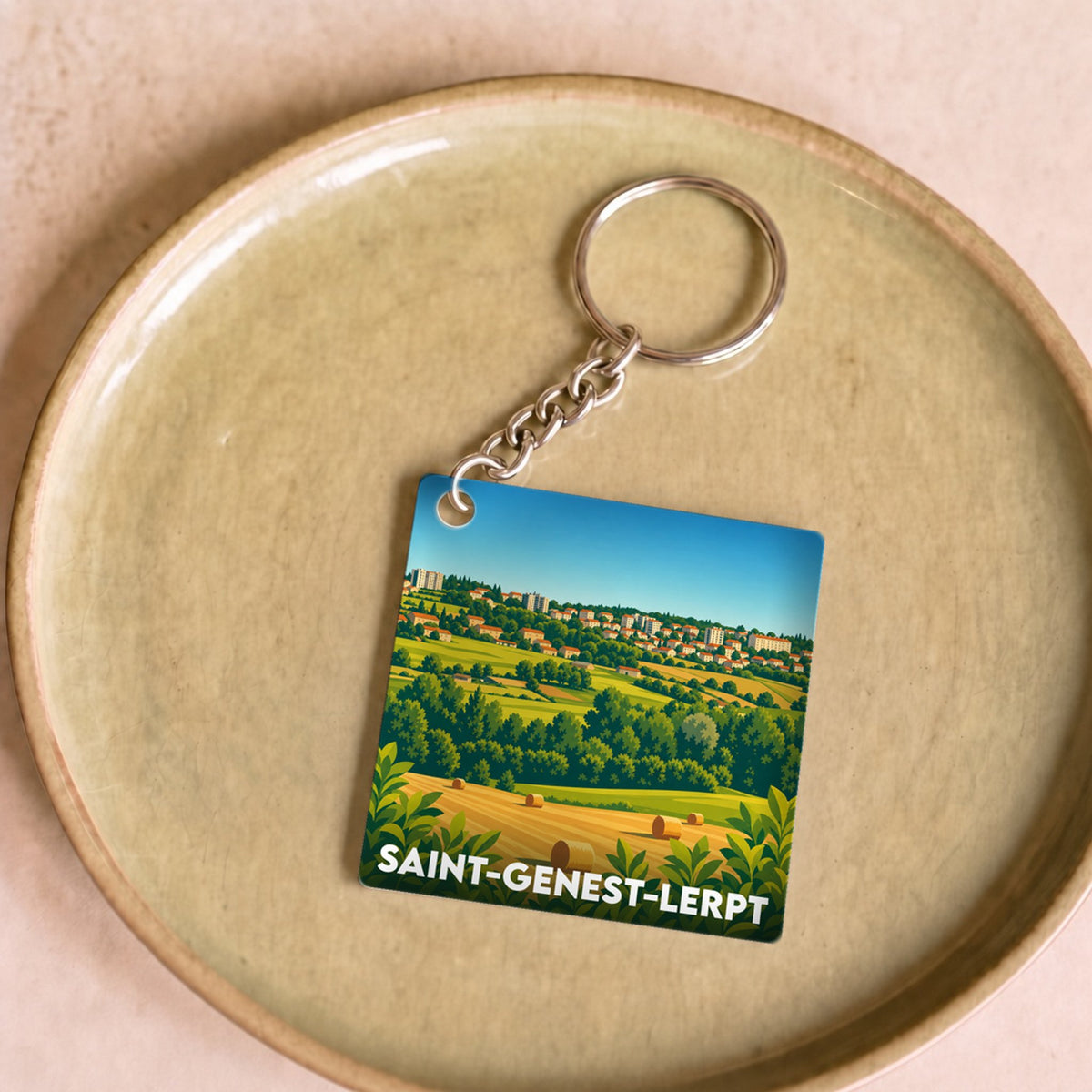 Porte-clés souvenir de la ville de Saint-Genest-Lerpt avec une illustration stylisée de son paysage vallonné.
