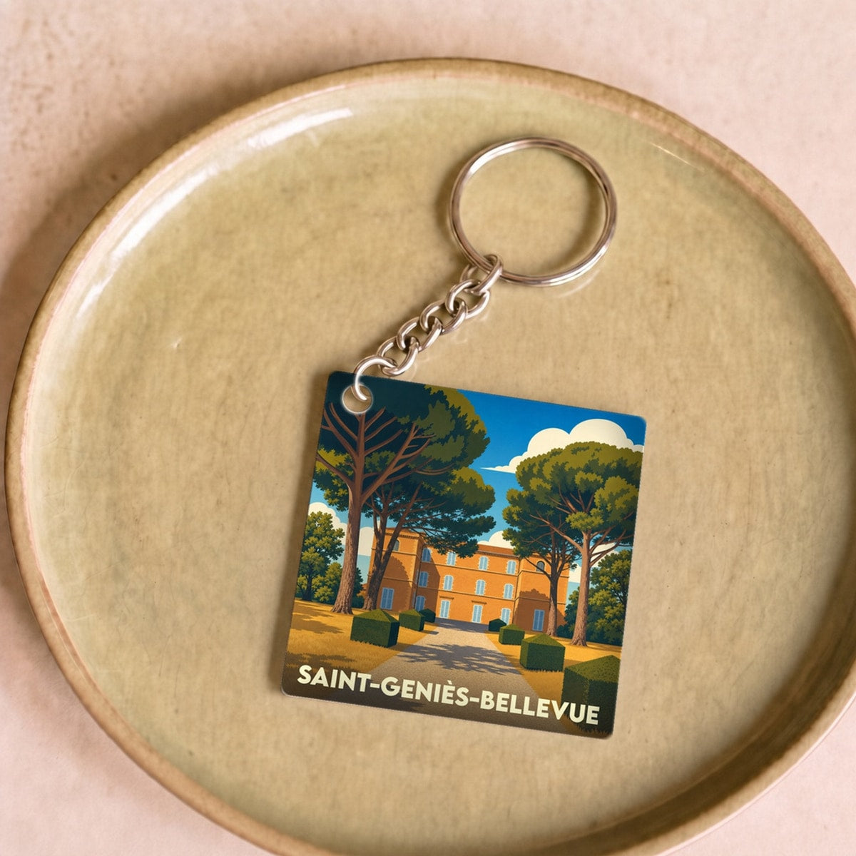 Porte-clés souvenir de la ville de Saint-Geniès-Bellevue avec une illustration stylisée d'un château.