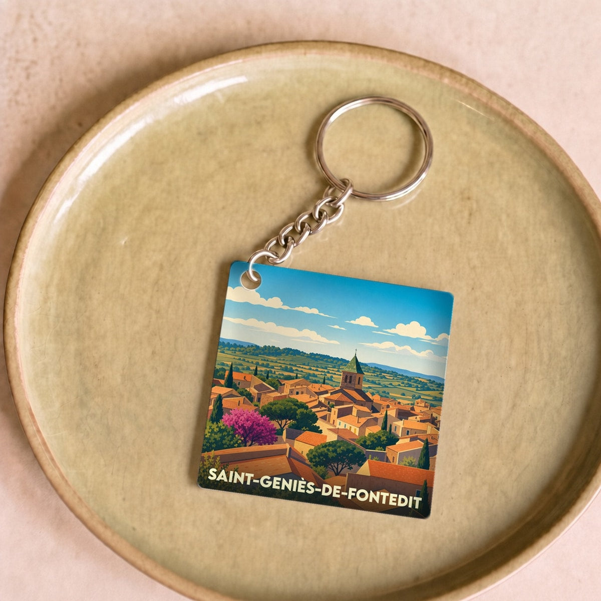 Porte-clés souvenir de la ville de Saint-Geniès-de-Fontedit avec une illustration stylisée.