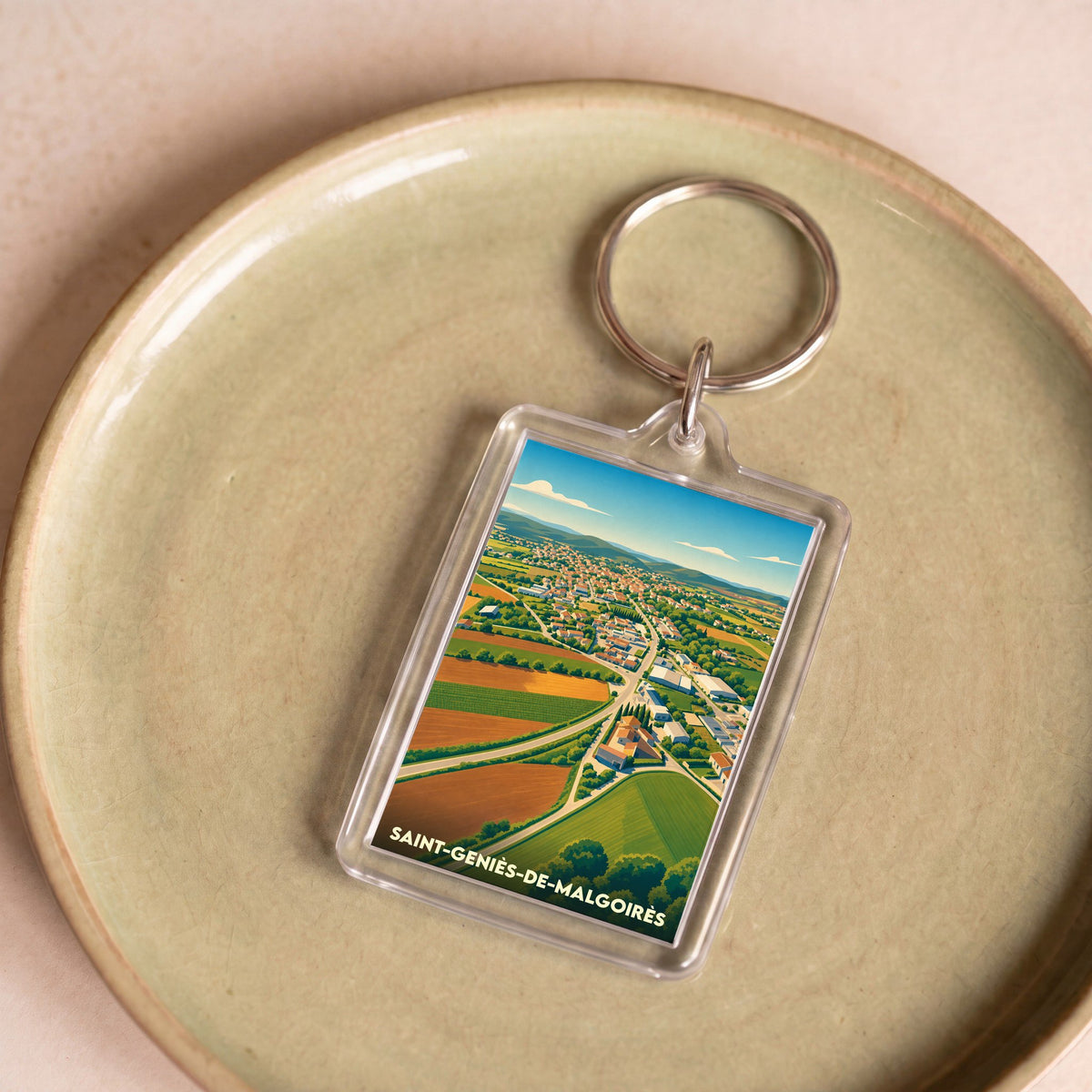 Porte-clés souvenir de la ville de Saint-Geniès-de-Malgoirès avec une illustration aérienne et stylisée de ses paysages.