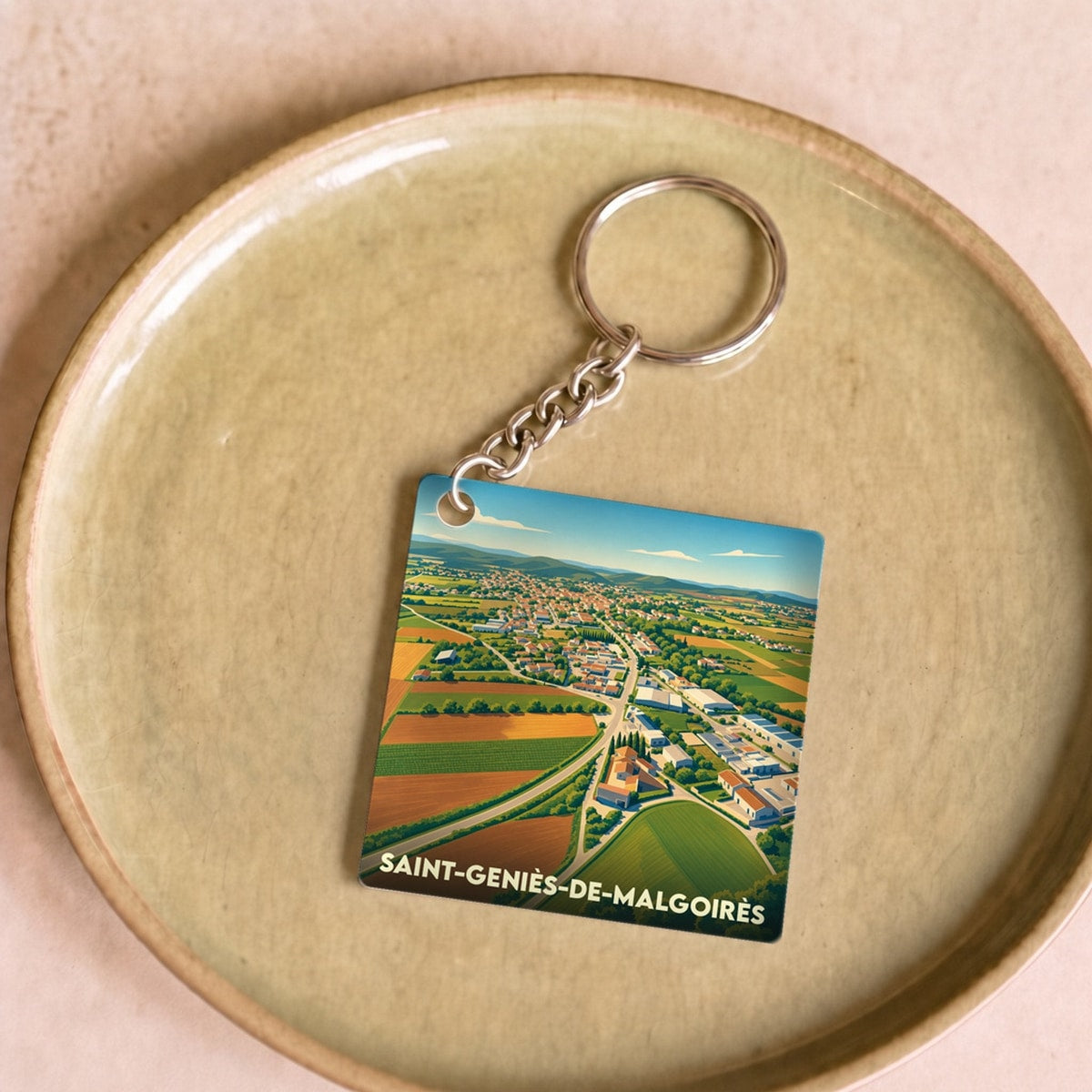 Porte-clés souvenir de la ville de Saint-Geniès-de-Malgoirès avec une illustration aérienne et stylisée de ses paysages.